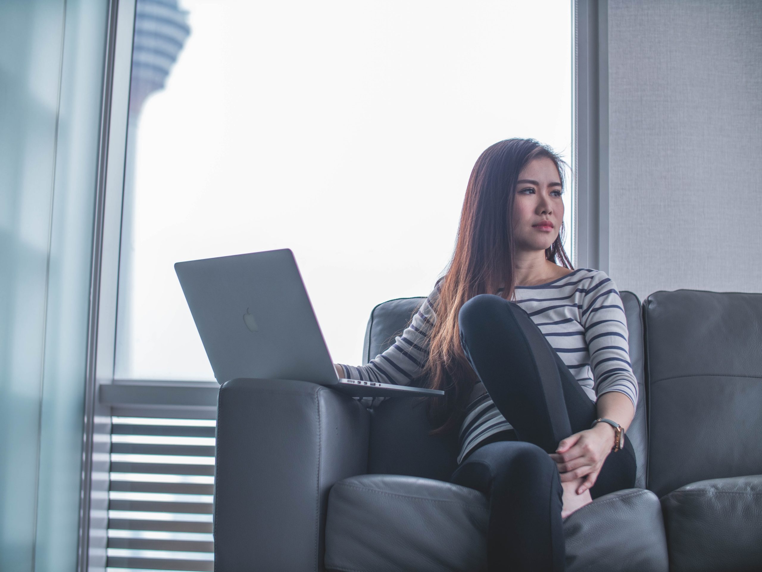 Woman Sitting On Couch While Using Laptop Computer